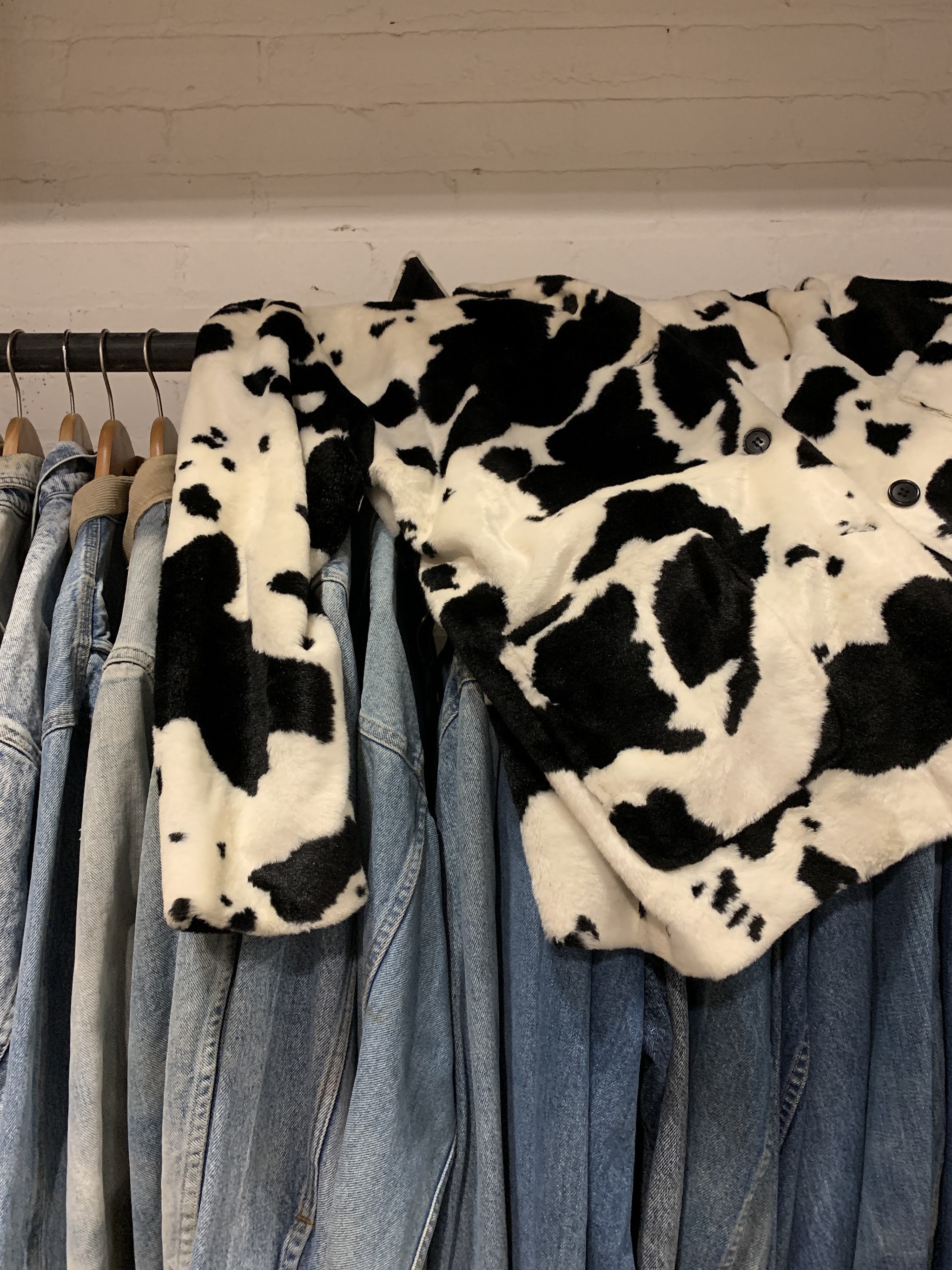 Cow print faux fur jacket hanging over denim jackets