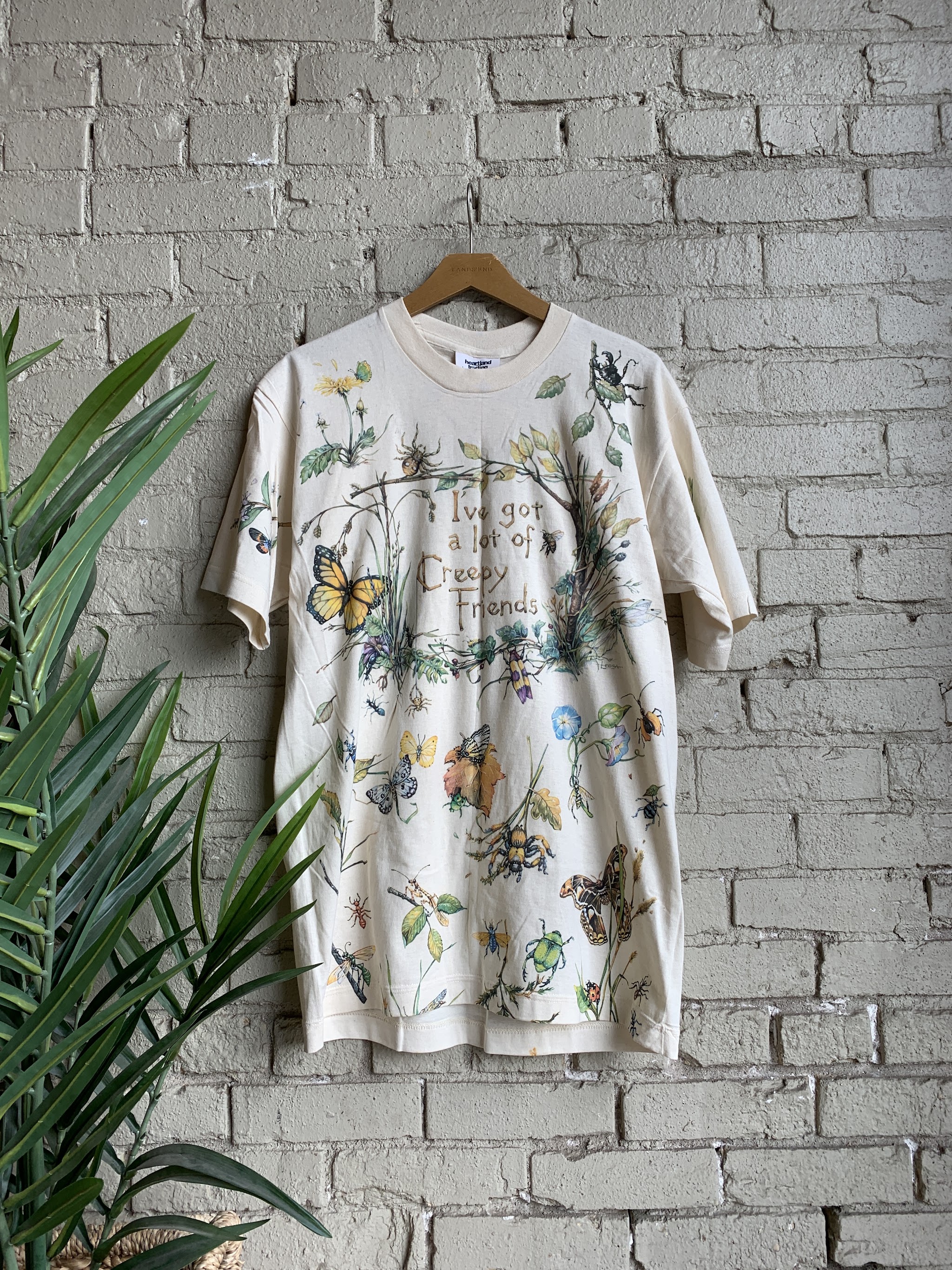 Butterfly and wildflower print t-shirt against white painted brick