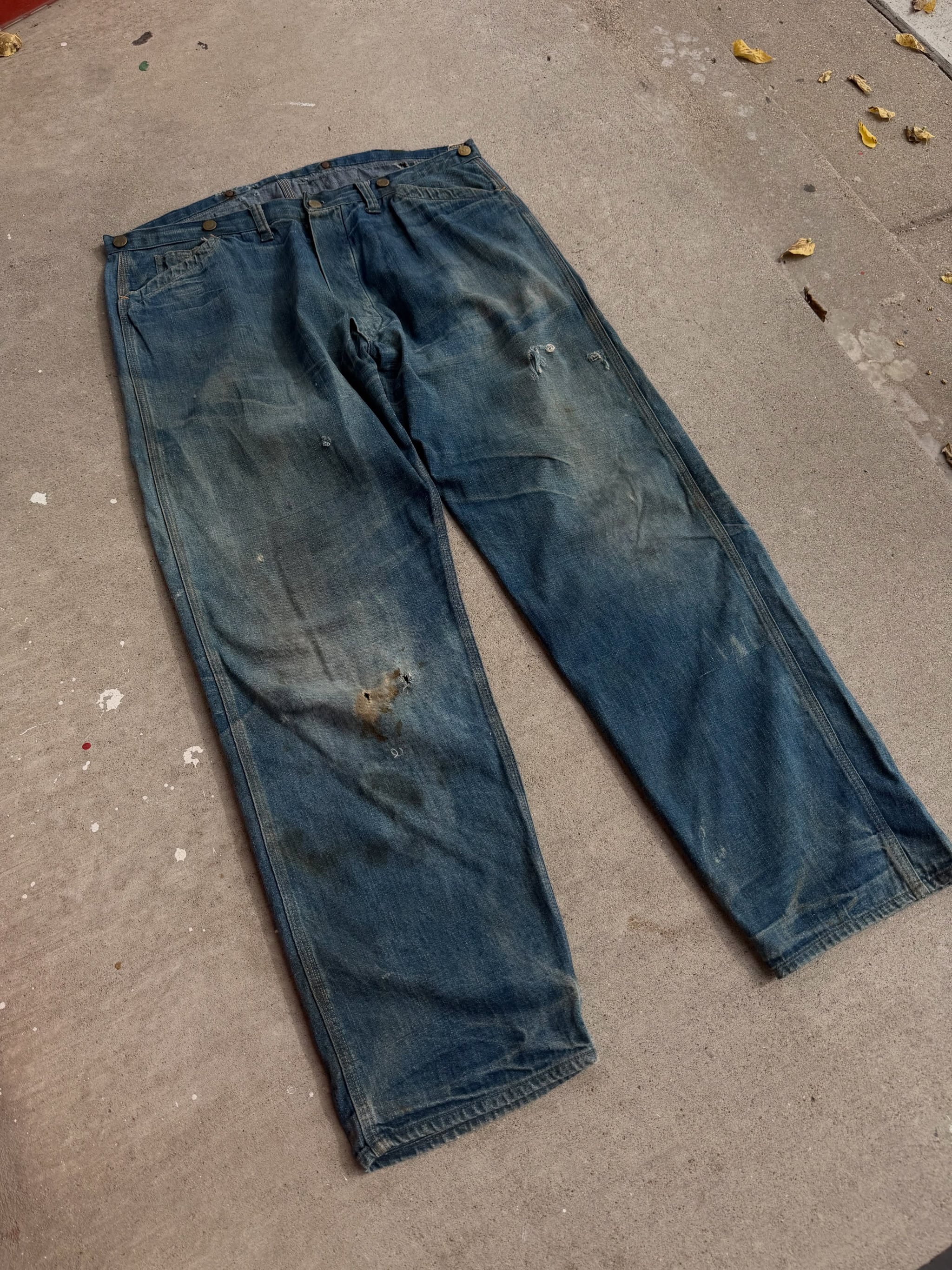 Faded early twentieth century Big 3 Triple Stitch denim overalls laid flat on concrete